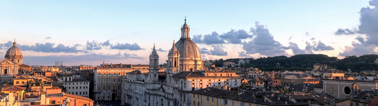 Panorama di Roma: l'immagine mostra i tetti di Roma al tramonto. Si intravedono uno scorcio di piazza Navona con la cupola e i campanili della chiesa di Sant’Agnese in Agone.